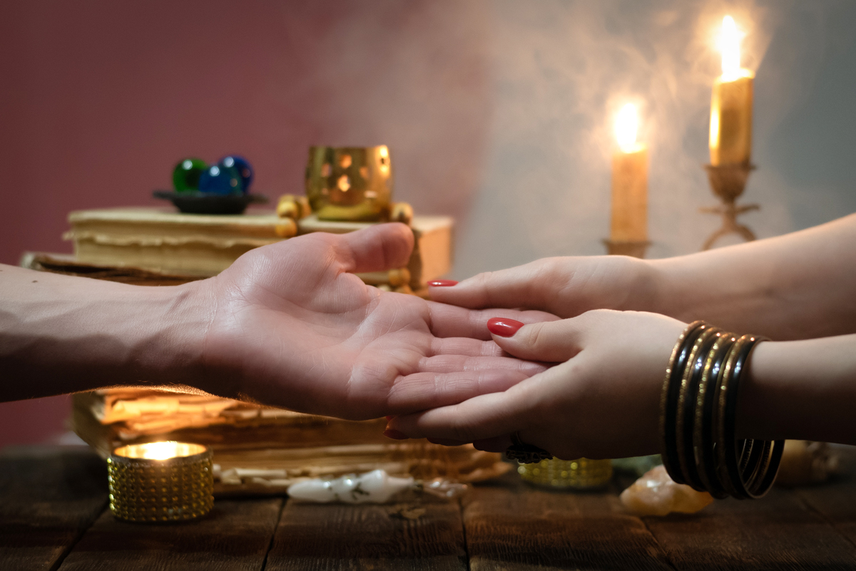 A close up of a Psychic’s hands doing a Palm Reading on a client’s hand.